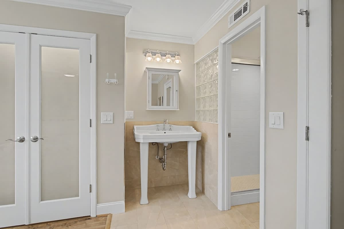 Your elegant bathroom features a classic pedestal sink and spacious glass shower with luxury finishes.