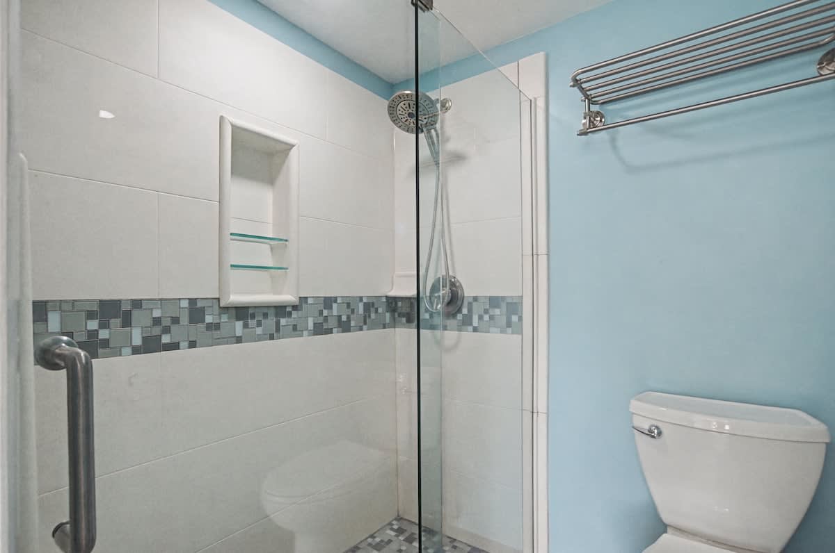 Enjoy a spacious walk-in shower with elegant mosaic tile details and fresh fluffy towels.