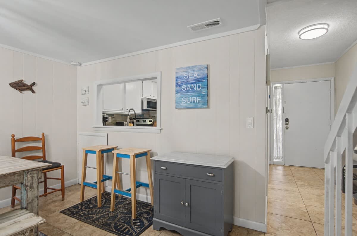 Your coastal dining nook features charming beachy decor and convenient kitchen window service for easy meal prep and entertaining.