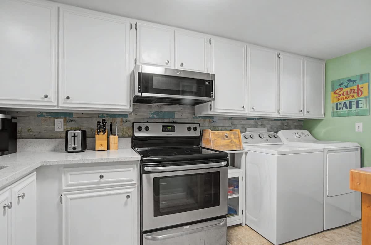 Fully equipped kitchen with modern appliances and crisp white cabinets offer a comfortable home-away-from-home experience.
