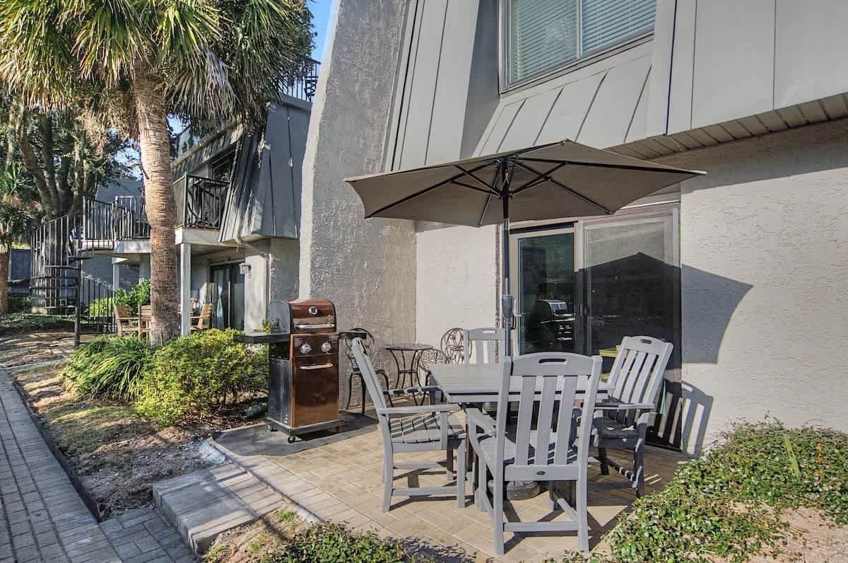 Your private patio awaits with comfortable dining seating, BBQ grill, and tropical palm shade for perfect outdoor meals.
