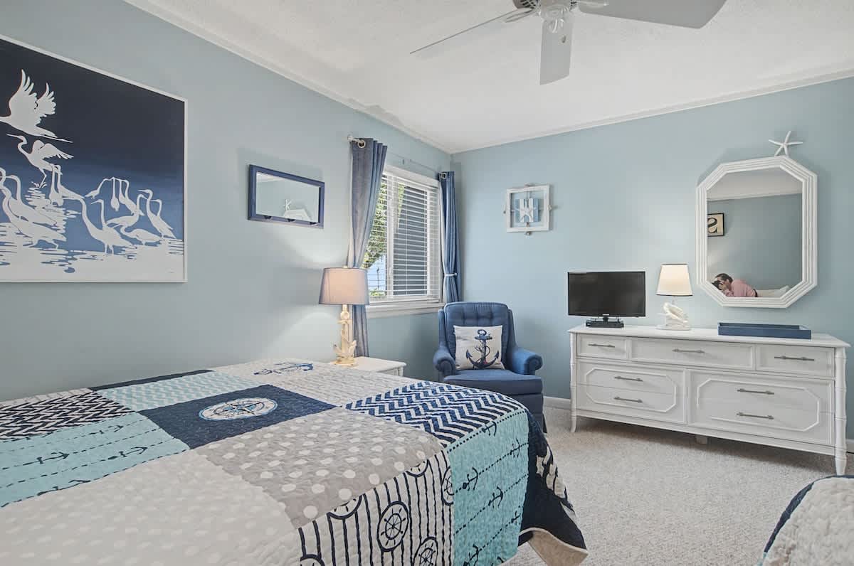Enjoy your nautical sanctuary with calming coastal blues, seaside artwork, and gentle ceiling fan breezes creating perfect comfort.