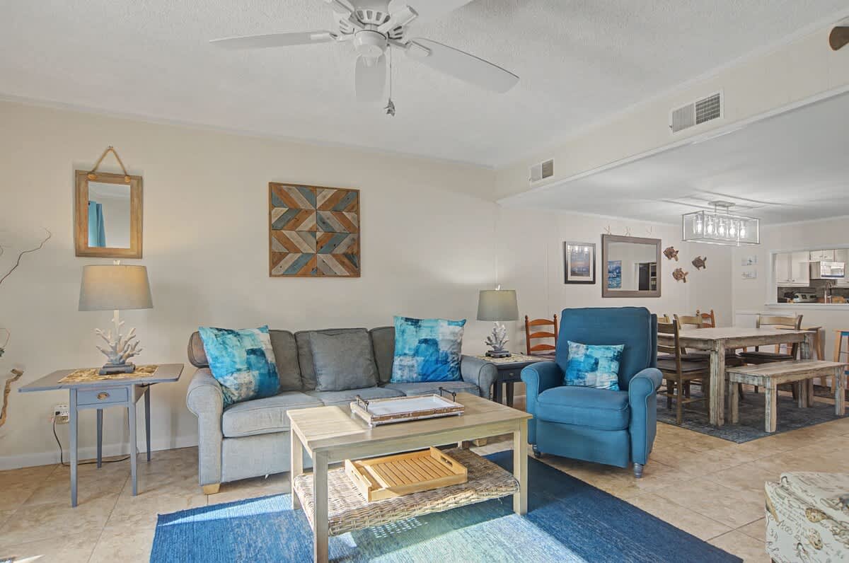 Bright and welcoming living space designed for gathering, featuring comfortable seating, abundant natural light, and an open layout perfect for unwinding after a day at the beach.