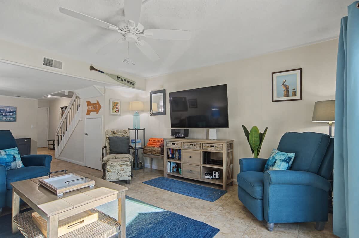 Relax in your bright living room with coastal blues, comfy seating, and entertainment center - perfect for unwinding after beach days.