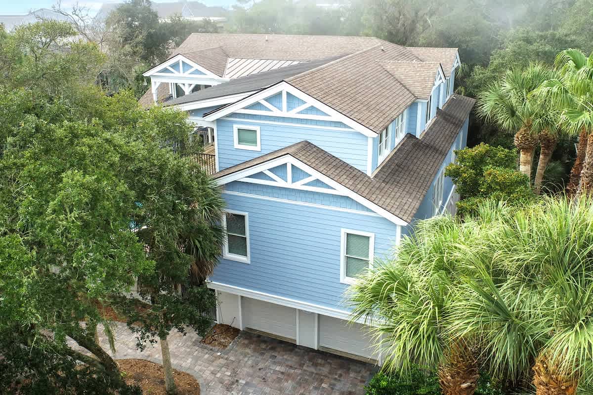 Charming coastal home nestled among lush tropical palms and mature landscaping in a peaceful residential setting.