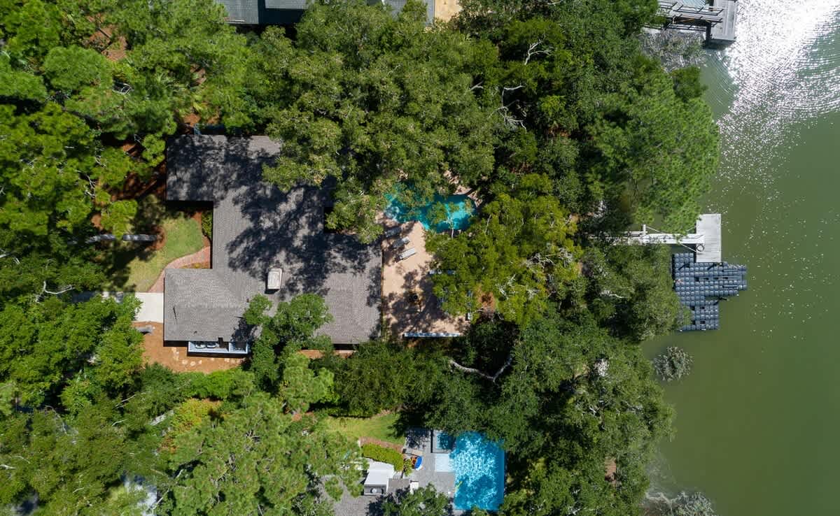 Stunning lakefront property showcasing private waterfront access, secluded swimming pool, and mature tree-lined grounds offering ultimate tranquility.
