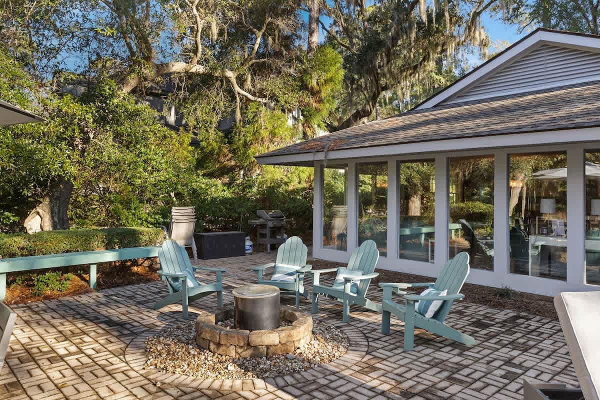 Gather around the fire pit on this charming paver patio, surrounded by mature trees and comfortable seating.