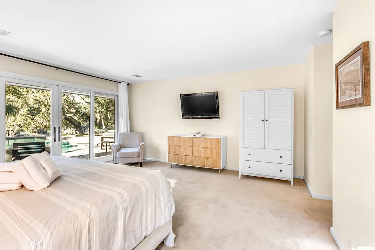 Your spacious bedroom features a comfortable seating area and TV for relaxation, with garden views through sliding doors.