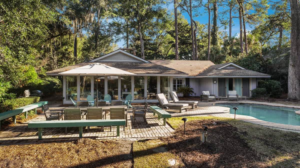 Charming cottage nestled among towering trees features a sparkling pool and spacious deck for ultimate relaxation.