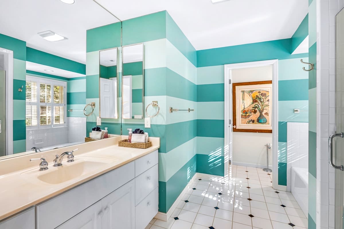 Step into your bright coastal bathroom featuring bold turquoise stripes, spacious vanity, and cheerful natural light streaming through plantation shutters.