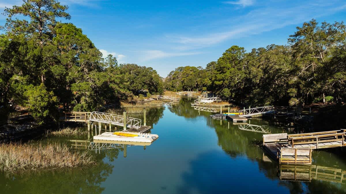 Serene waterway lined with private docks and lush trees, offering peaceful boating access and natural beauty in the surrounding area.