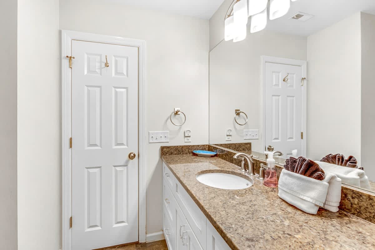 Your spacious bathroom features elegant granite countertops, crisp white cabinetry, and thoughtful touches that make your daily routine feel luxurious.