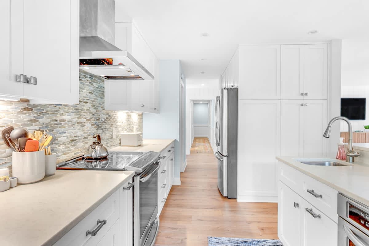 Your dream kitchen awaits with gleaming white cabinets, stunning tile backsplash, and premium stainless steel appliances ready for culinary adventures.