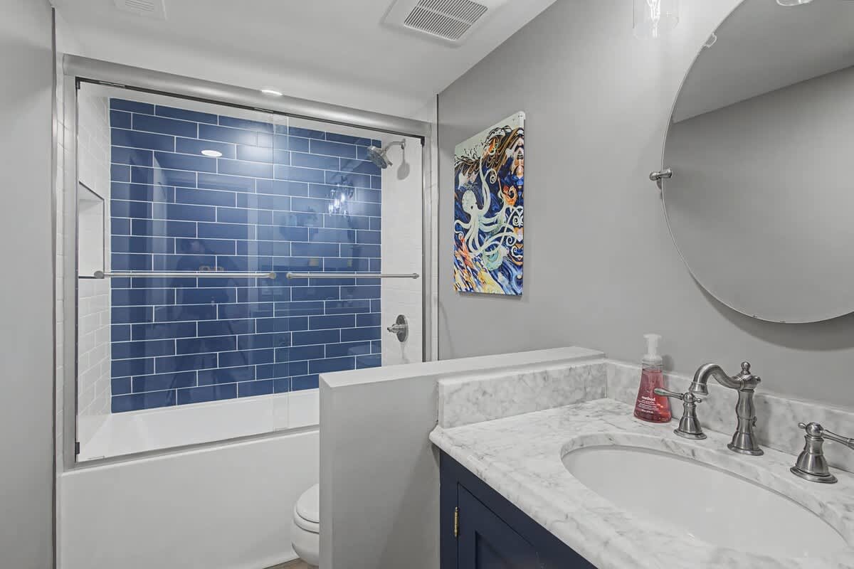 Your elegant bathroom features a marble vanity and striking blue subway tile shower, creating a spa-like retreat for your morning routine.