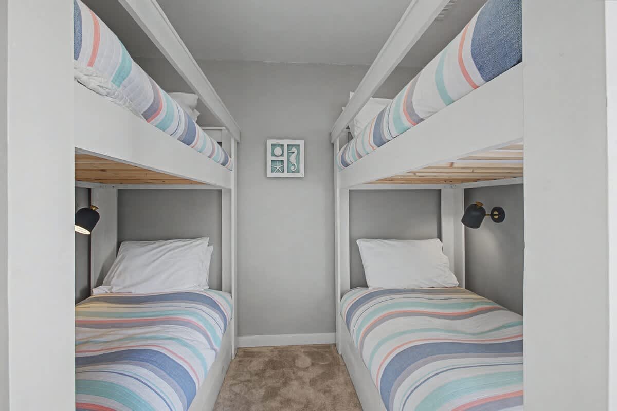 Cozy bunk room with soft striped linens and individual reading lights for your perfect night's rest.