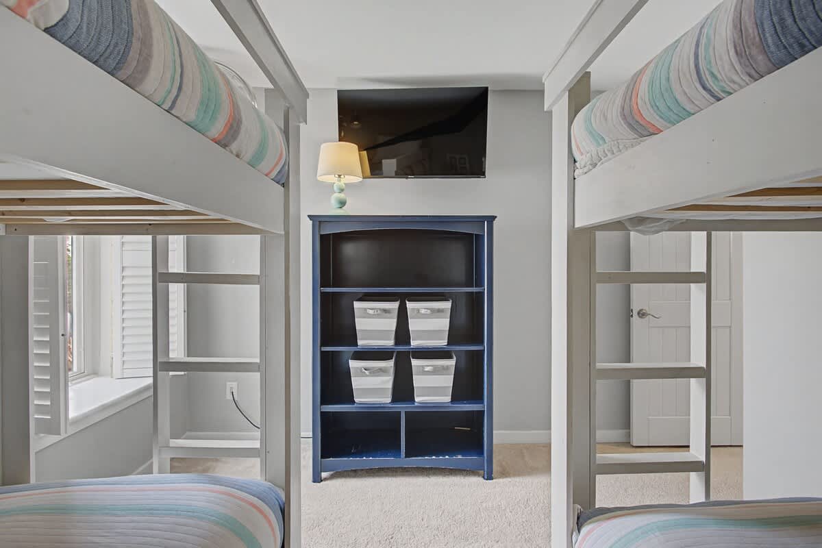 Your family will love this cheerful bunk room with four comfortable beds, organized storage, and a mounted TV for movie nights together.