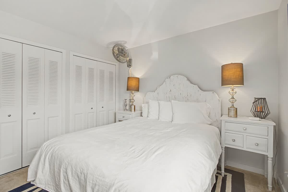 Sink into crisp white linens and let the warm lamp glow create your perfect bedtime ambiance in this serene retreat.