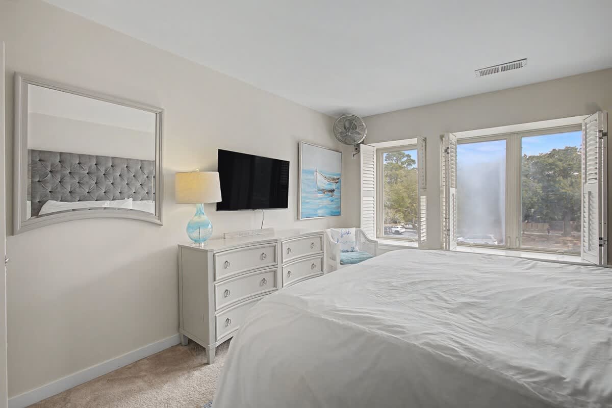 Wake up to serene forest views in your elegant bedroom, complete with plush bedding and peaceful natural light streaming through windows.