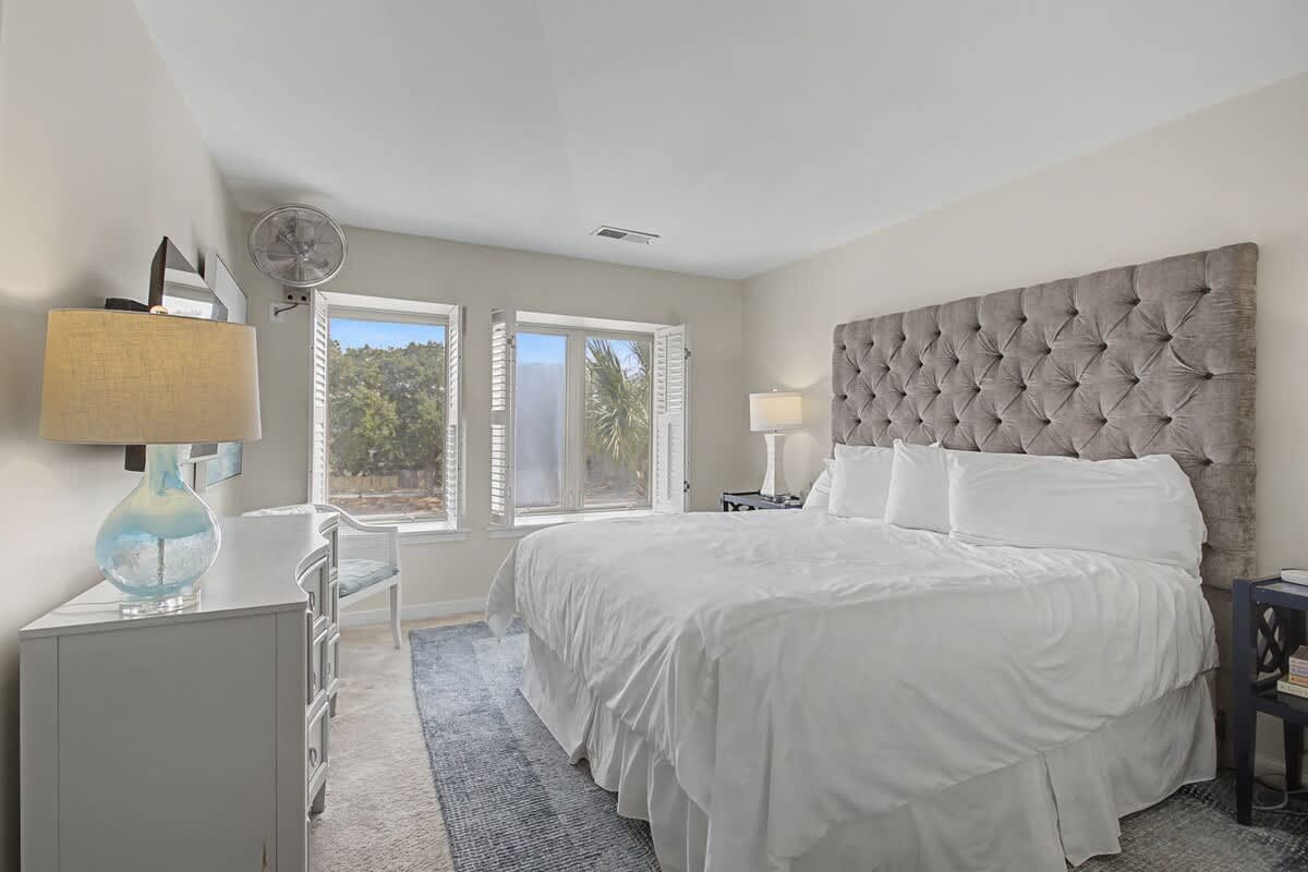 Sink into crisp white linens beneath this stunning tufted headboard, while natural light streams through your windows overlooking lush greenery.