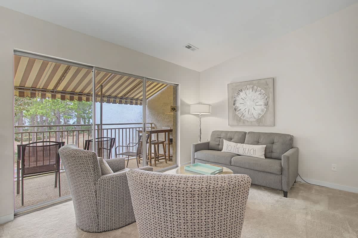 Unwind in your bright living room with comfy seating and ocean-themed decor, opening to a private covered balcony.