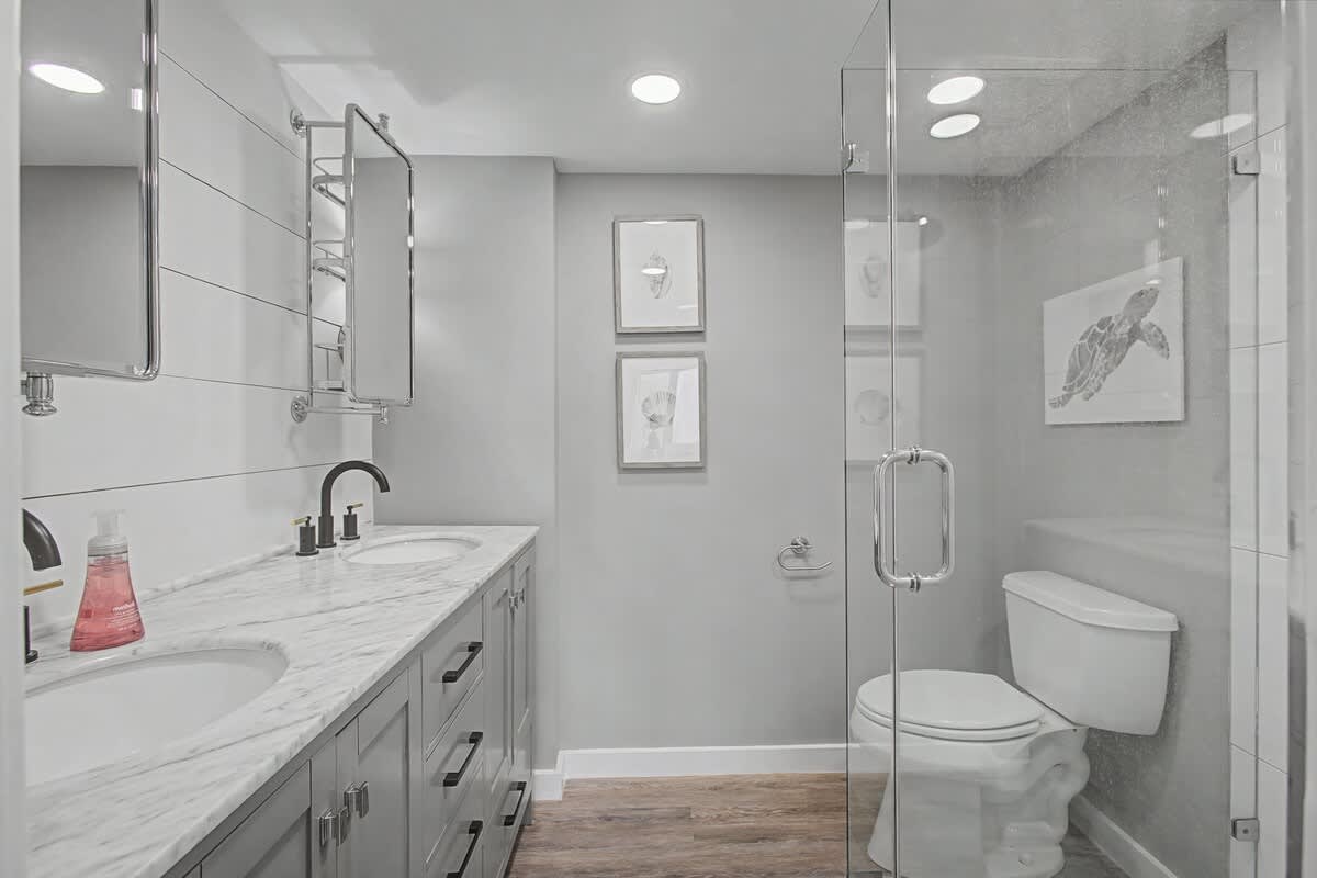 Enjoy your marble countertops and sleek glass shower in this beautifully renovated bathroom with modern gray tones.