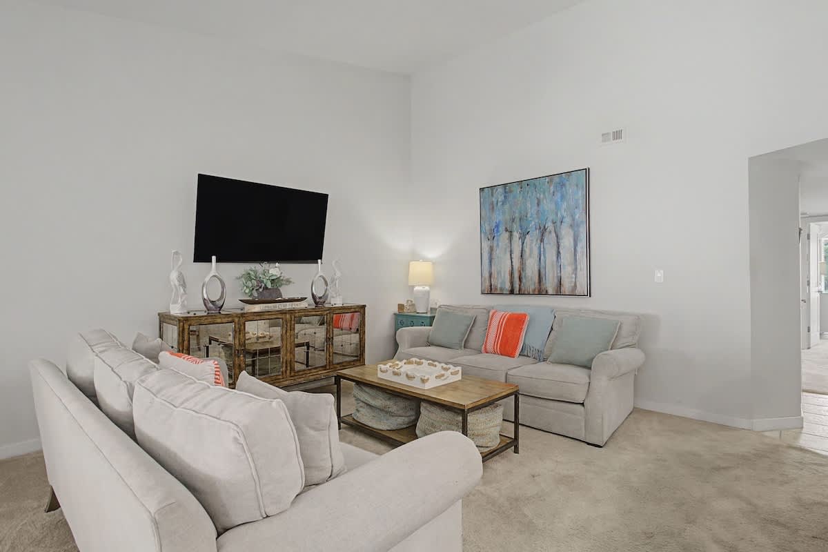 Sink into plush gray sofas in your bright living space, where thoughtful touches and modern art create the perfect backdrop for relaxing evenings.