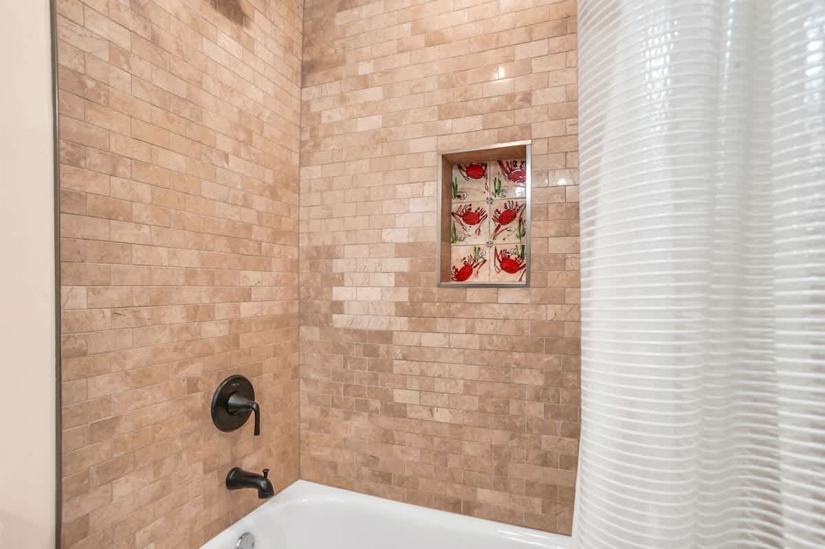 Soak in your beautifully tiled bathtub surrounded by elegant stone-look subway tiles and charming ceramic art details.