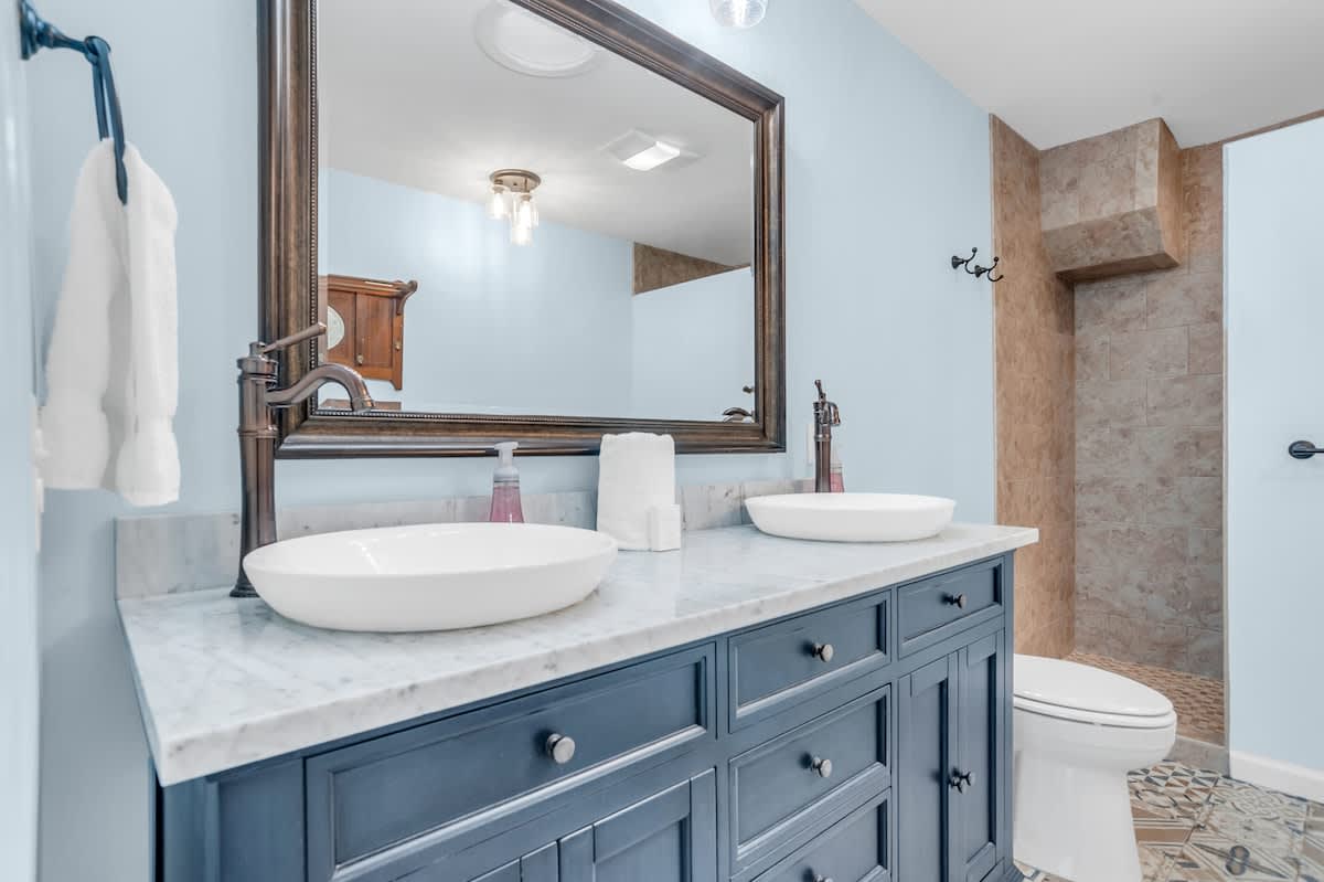 Unwind in your elegant bathroom featuring marble countertops, dual vessel sinks, and a luxurious stone-tiled shower for your perfect getaway.