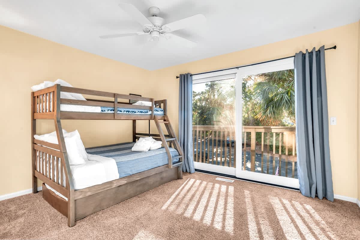 Sleep peacefully in this cozy bunk room where sunlight streams through your private balcony doors onto soft carpeting.