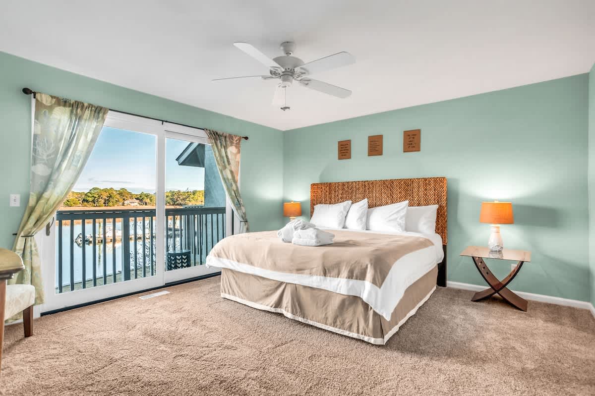 Wake up to stunning water views from your peaceful bedroom sanctuary, where soft mint walls and cozy furnishings create the perfect retreat.