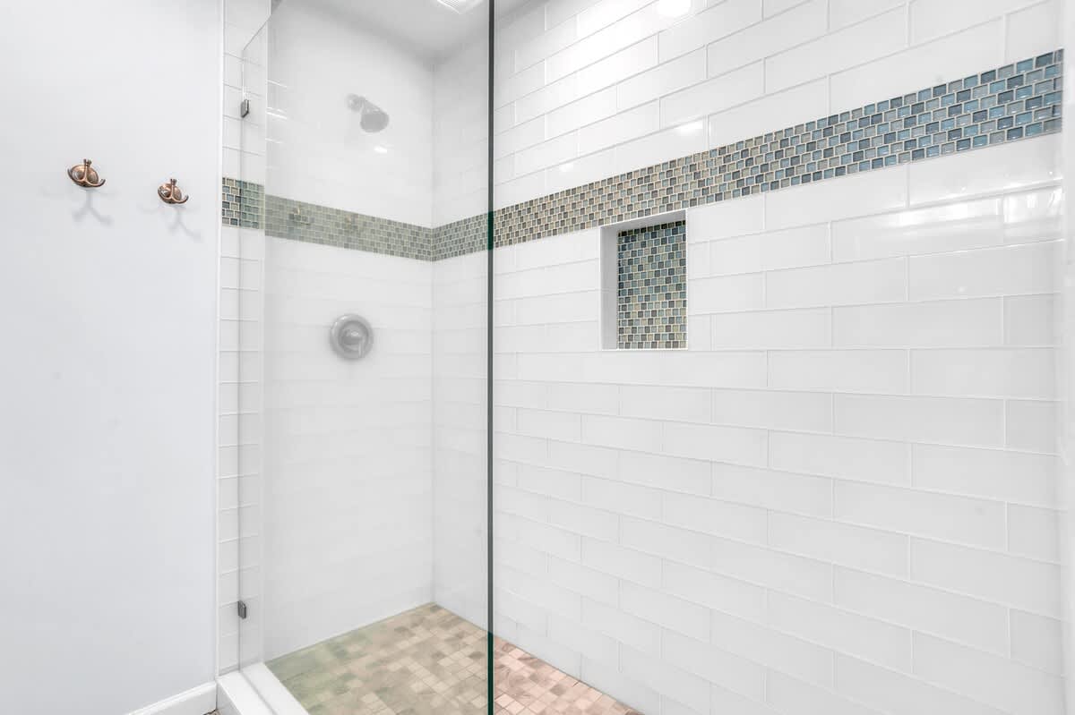 Step into your spacious walk-in shower with elegant mosaic tile accents and dual shower heads for the ultimate refreshing experience.