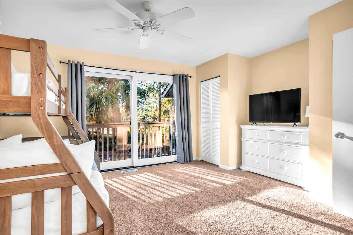 Relax in your bright bedroom with bunk beds, flat-screen TV, and private balcony overlooking tropical palms.