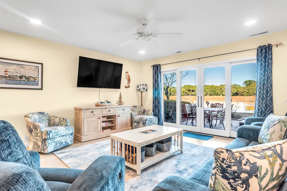 Relax in your spacious living room with coastal décor, perfect for family time and enjoying views of the outdoor dining area.