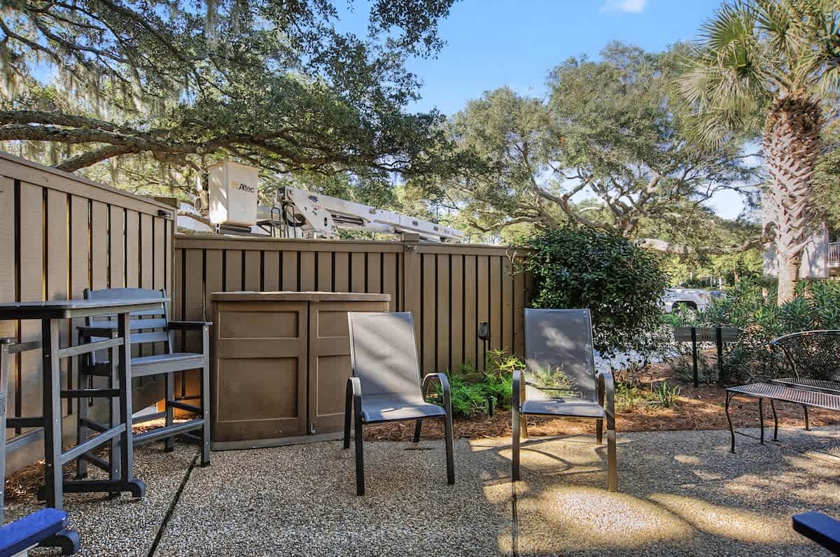 Relax in your private outdoor space with comfortable seating surrounded by lush greenery and mature trees.