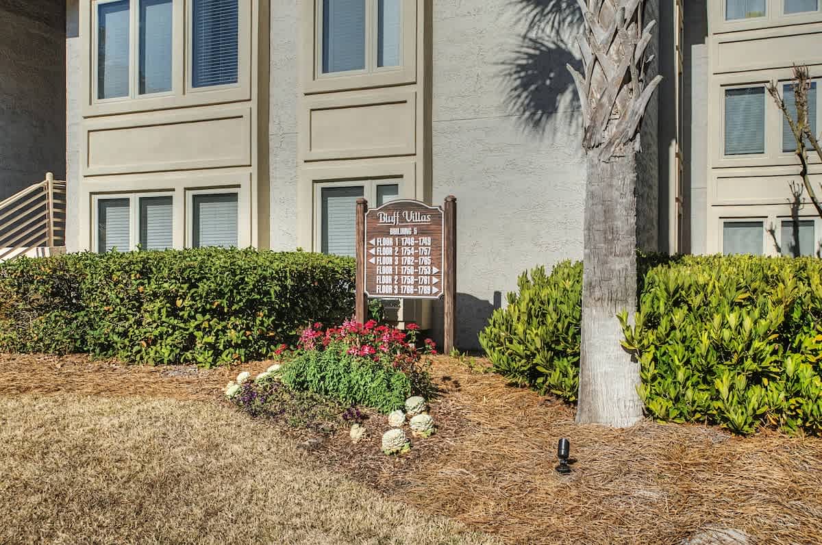 Welcome to Bluff Villas, where tropical landscaping and palm trees frame the entrance to your coastal retreat.