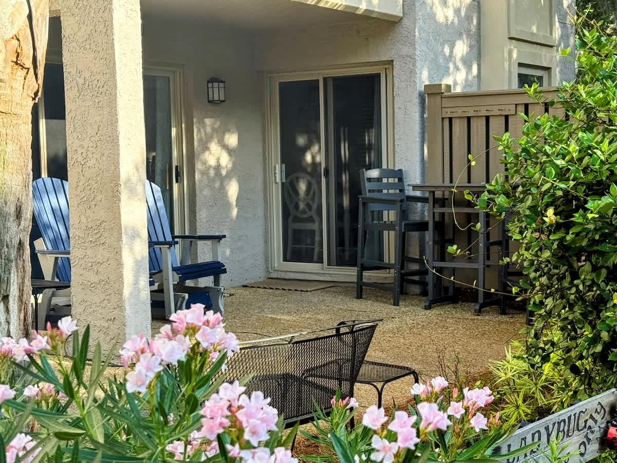 Your private patio welcomes you with comfortable seating surrounded by blooming flowers and lush greenery.