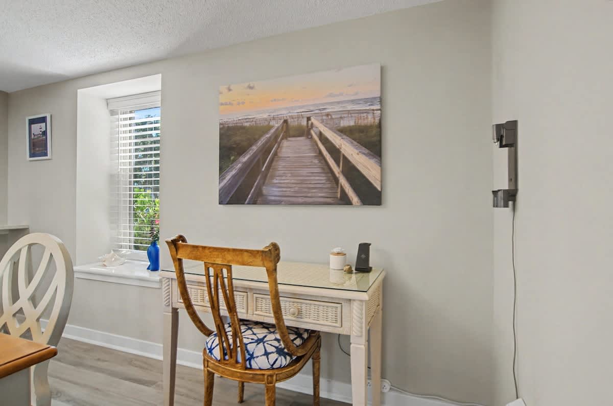 Your dedicated workspace features a charming wooden desk, comfortable chair, and inspiring beach boardwalk artwork to keep you motivated.