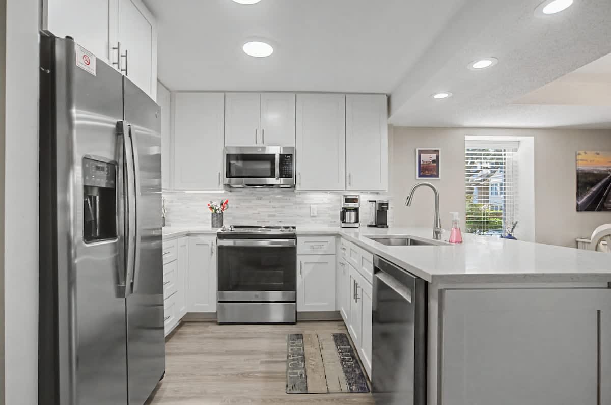 Your fully equipped modern kitchen features sleek white cabinets, stainless steel appliances, and plenty of counter space for preparing meals during your stay.