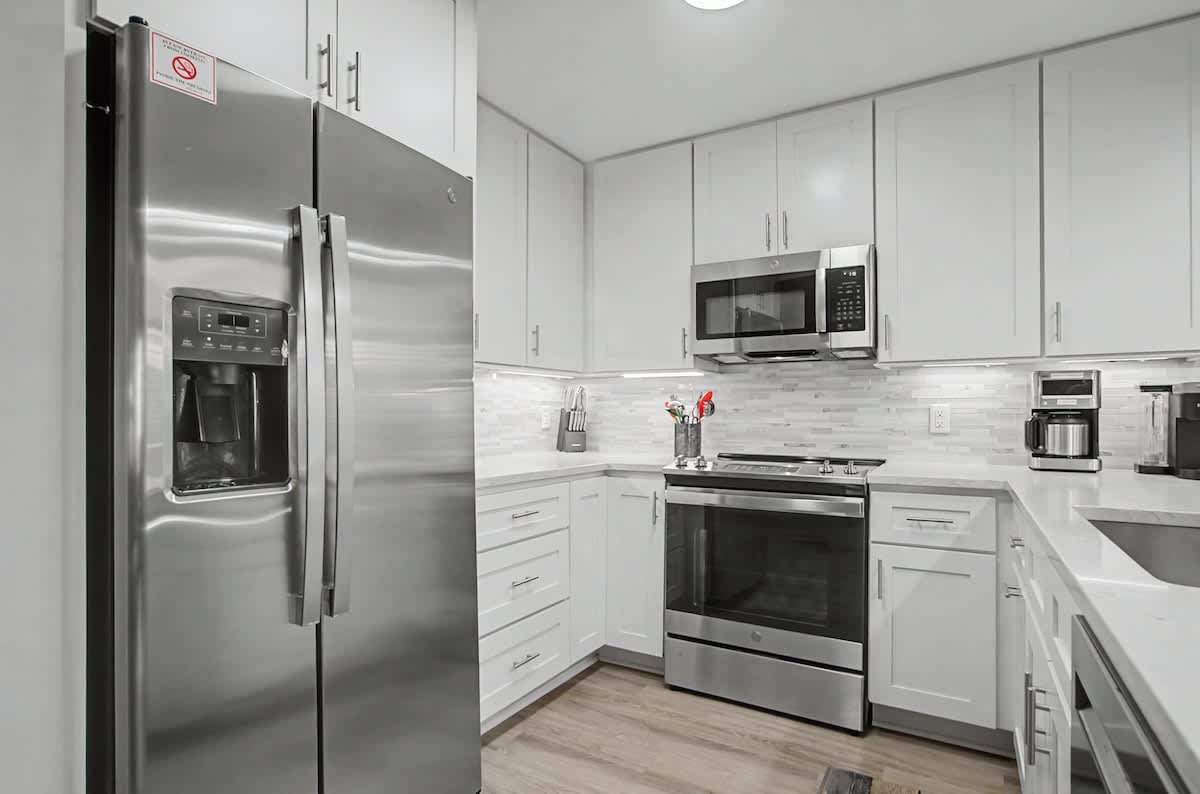 Your fully equipped kitchen features sleek white cabinets, stainless steel appliances, and elegant marble backsplash for effortless meal preparation.