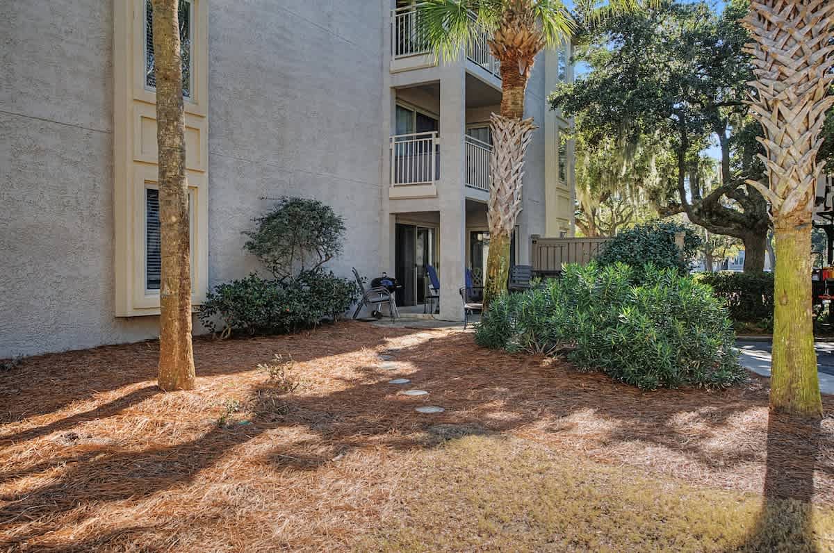 Multi-story vacation rental building nestled among mature palm trees and landscaped grounds with private balconies.
