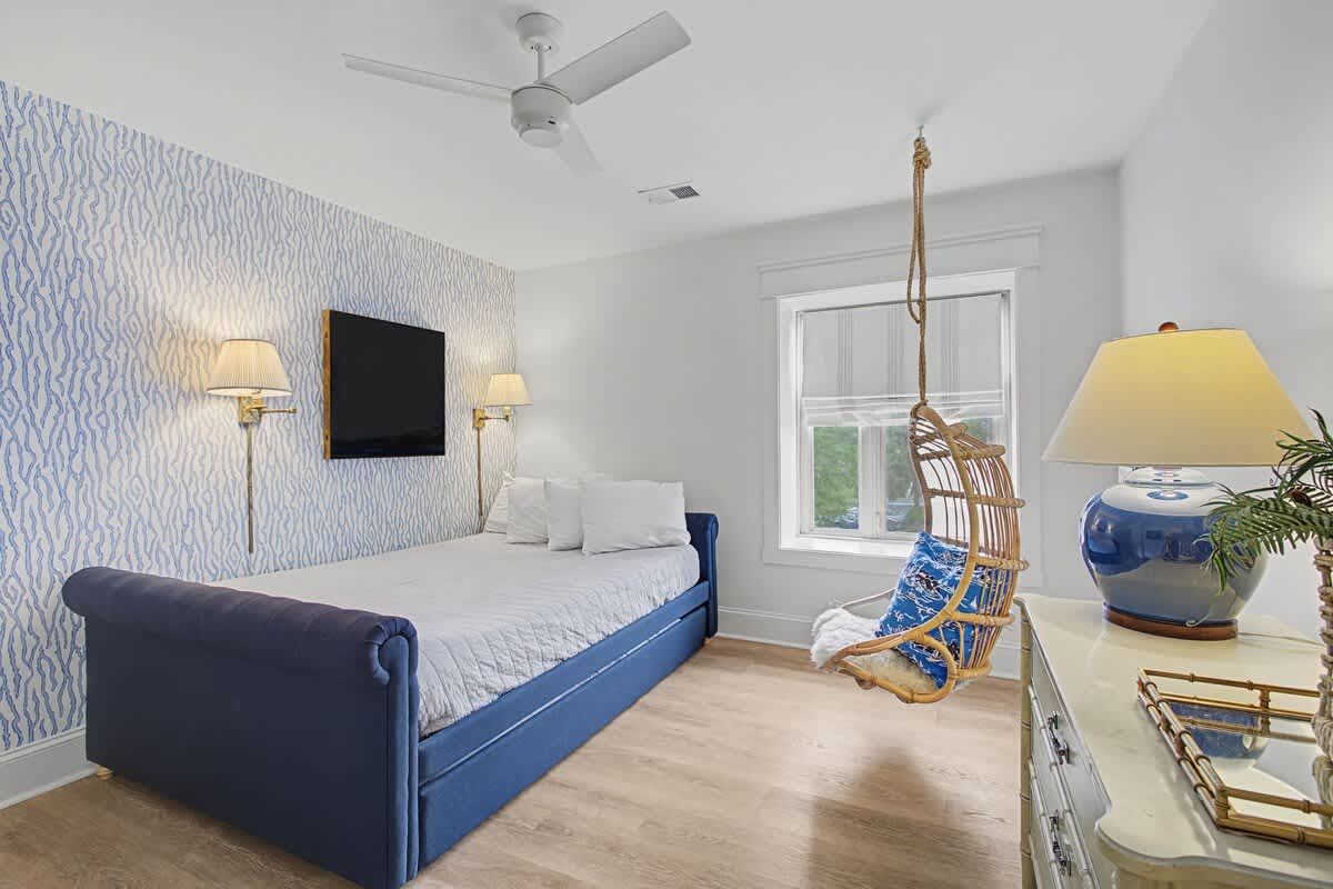 Rest peacefully in your stylish bedroom featuring elegant blue accents and a charming hanging chair for quiet moments.