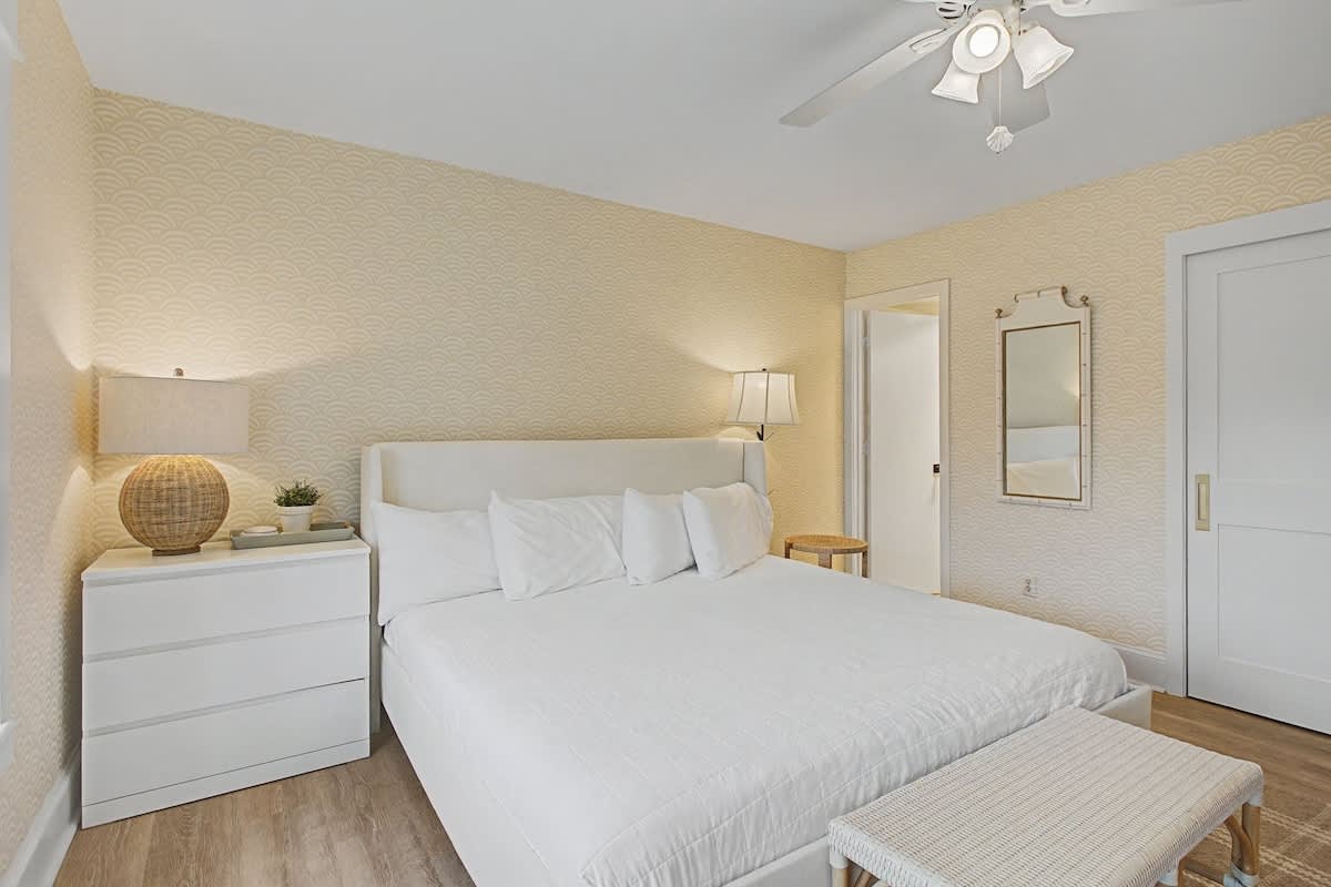 Sink into crisp white linens in your serene bedroom, where textured walls and natural wood accents create the perfect retreat for peaceful nights.
