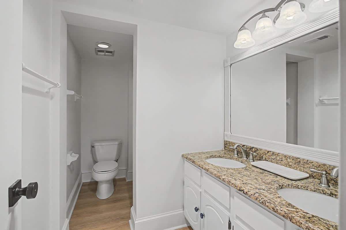 Step into your private bathroom sanctuary with granite countertops, dual vanity sinks, and a peaceful separate toilet alcove.