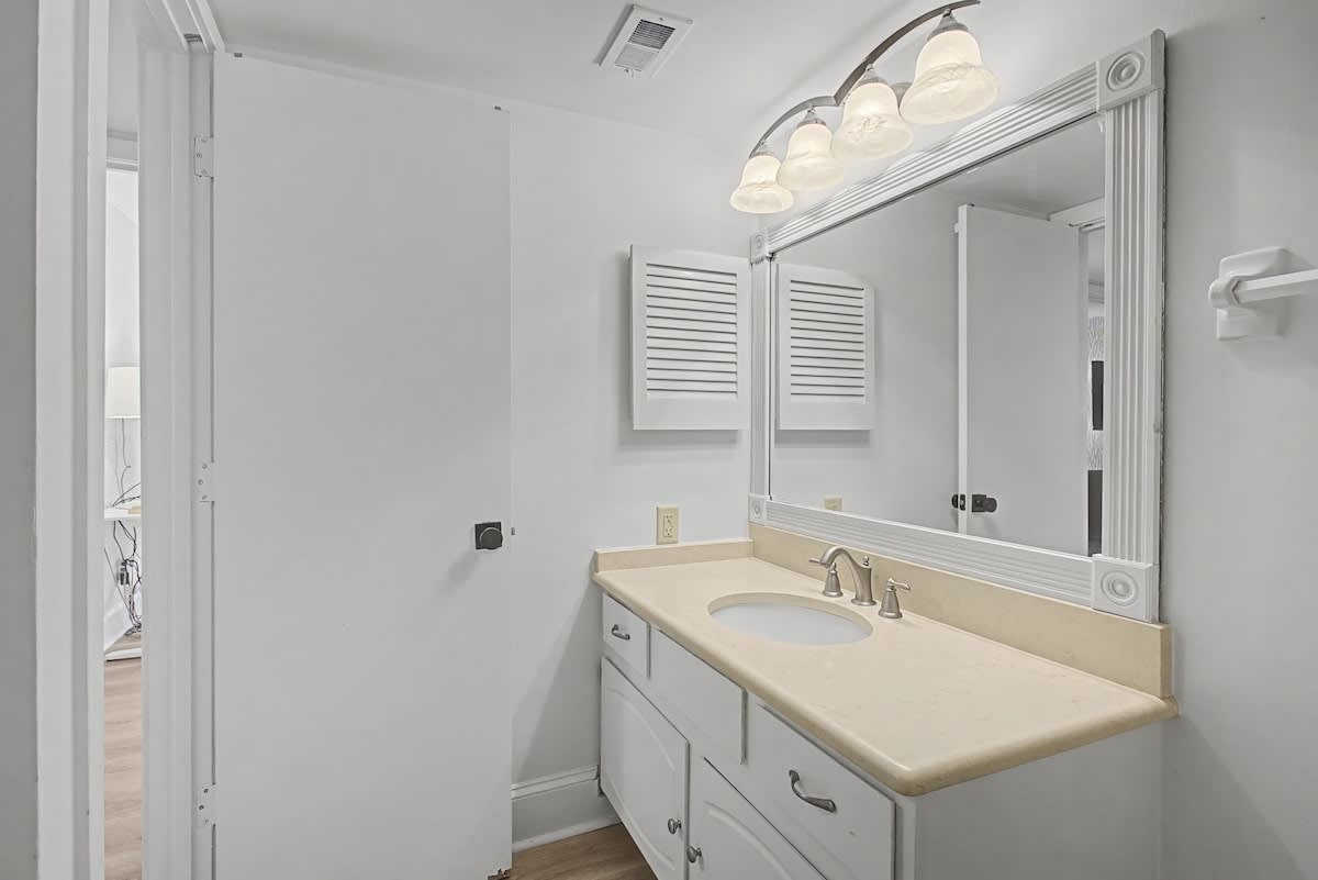 Step into your bright, pristine bathroom featuring elegant vanity lighting and ample counter space for your morning routine.