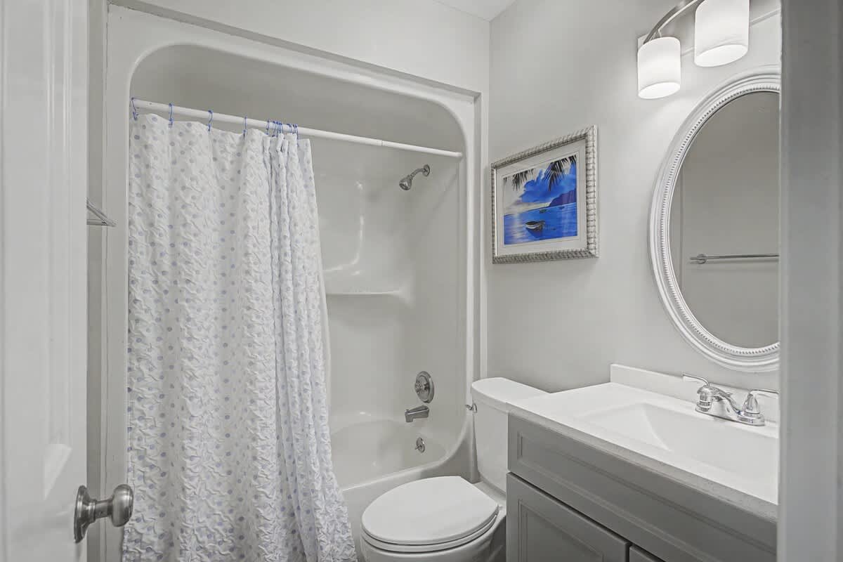 Step into your pristine bathroom featuring a relaxing tub-shower combo, elegant vanity, and thoughtful coastal artwork that adds serenity to your daily routine.