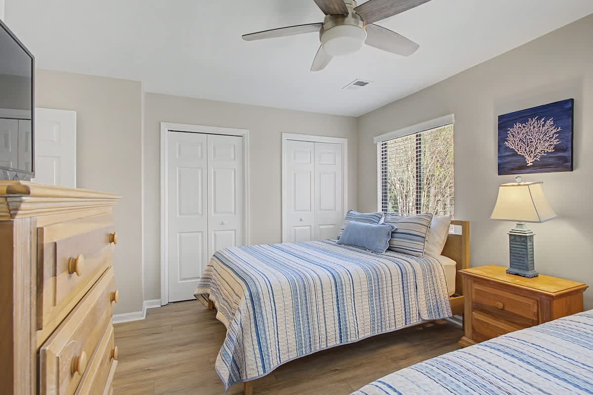 Drift off peacefully in your cozy bedroom with coastal blue linens and gentle ceiling fan breeze.