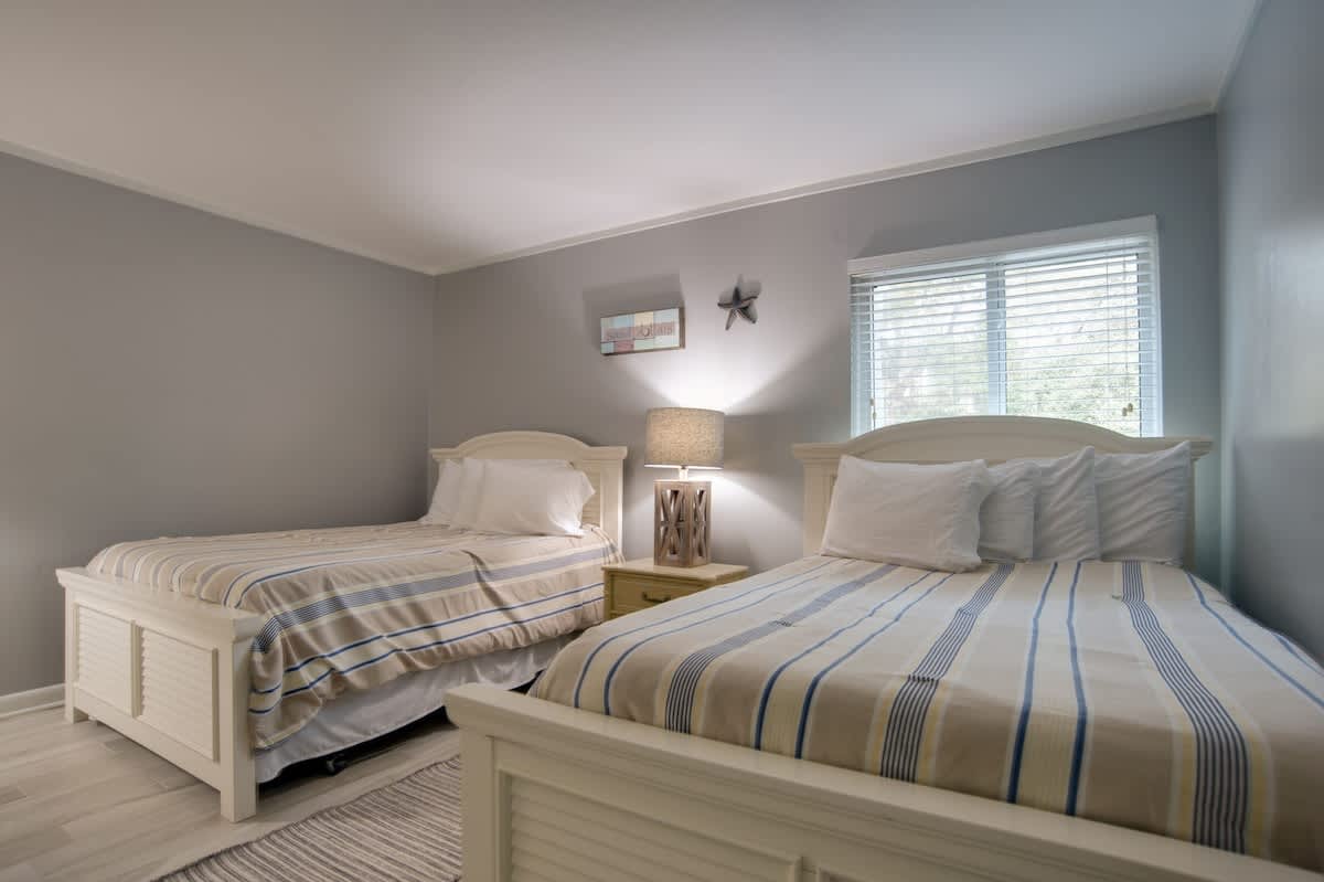 Drift off peacefully in your comfortable twin beds with soft striped linens and warm coastal charm throughout this serene bedroom.