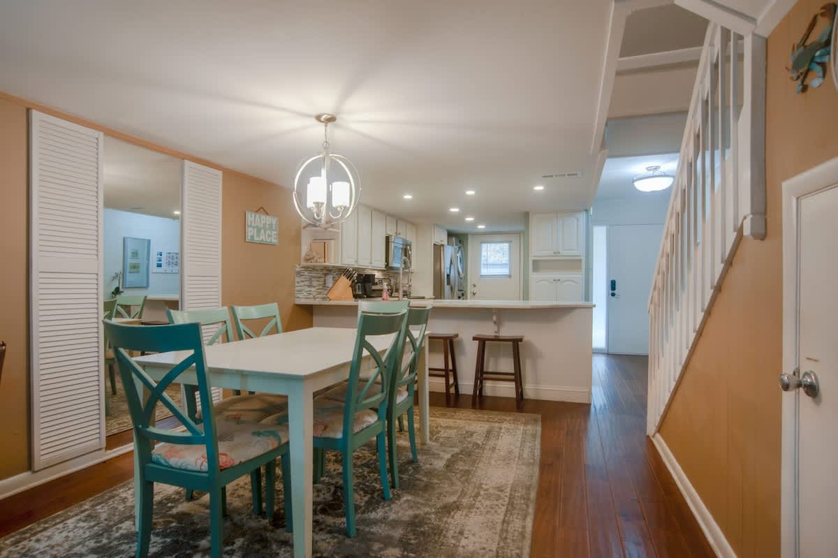 Your bright dining space flows seamlessly into the kitchen, where turquoise chairs add coastal charm to family meals together.
