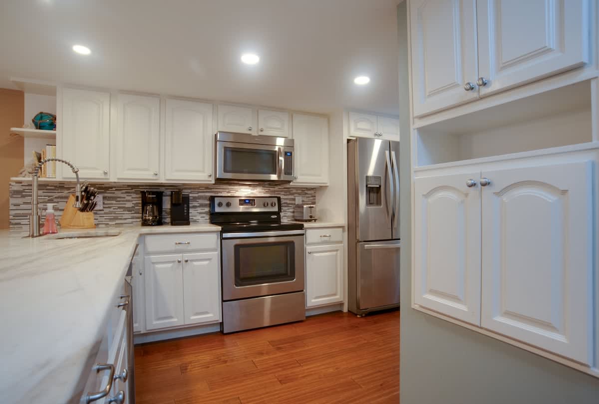 Your fully equipped kitchen features modern stainless steel appliances and elegant white cabinetry, perfect for preparing meals during your stay.
