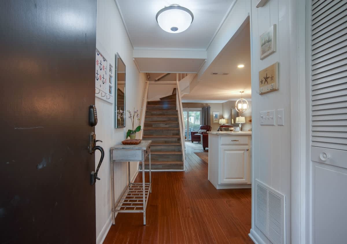 Step into your welcoming entryway where warm hardwood floors and coastal charm create the perfect homecoming feeling.